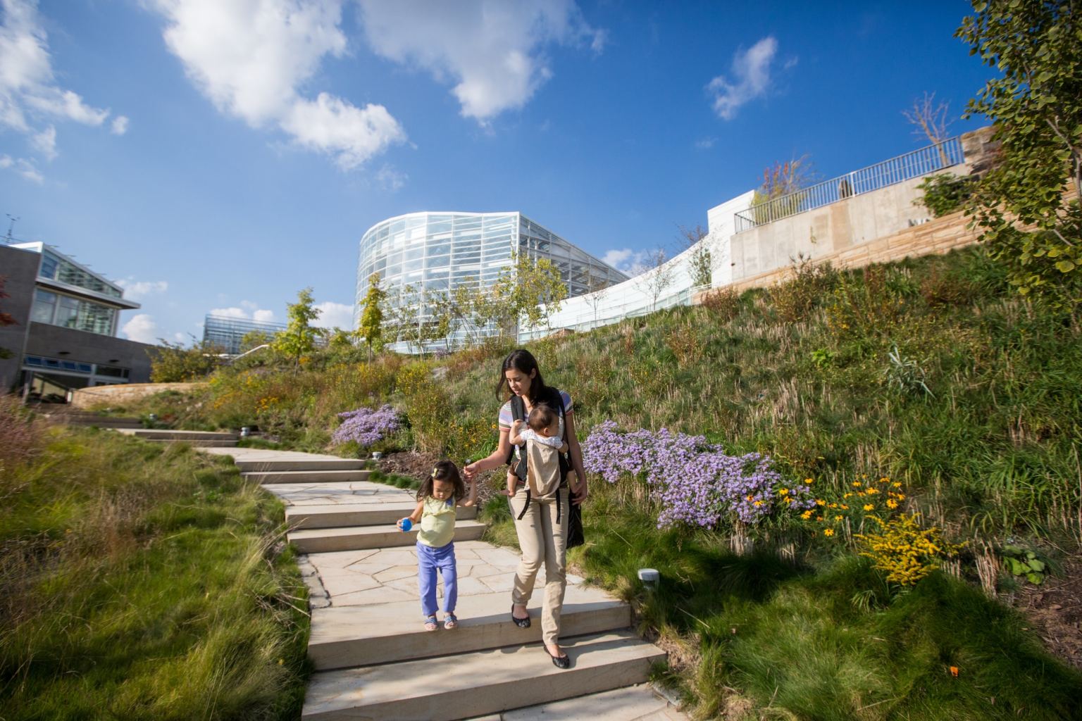 A mother with two small children walks down the steps of Phipps's nature walking tour next to the Center for Sustainable Landscapes.