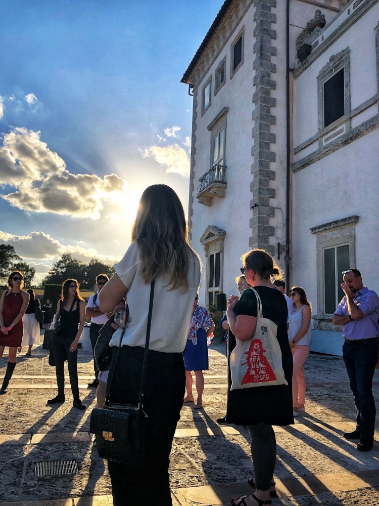 A group of people stand in a circle talking in front of Vizcaya Museum and Gardens.