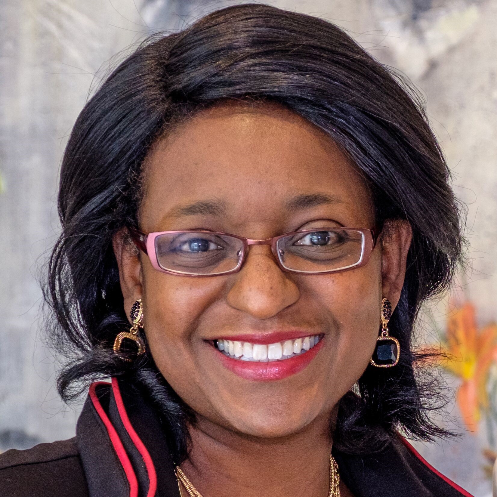Image of an Asian woman, Blinda Tate, with short dark hair wearing red wire rimmed glasses.