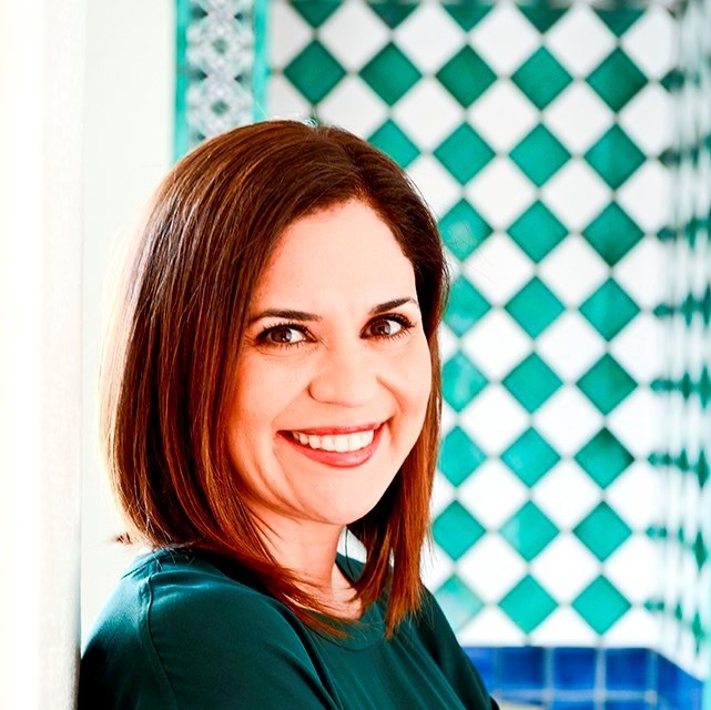 Image of Miki García, an Hispanic woman standing in front of a tiled wall.
