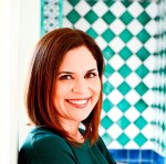 Image of Miki García, an Hispanic woman standing in front of a tiled wall. 