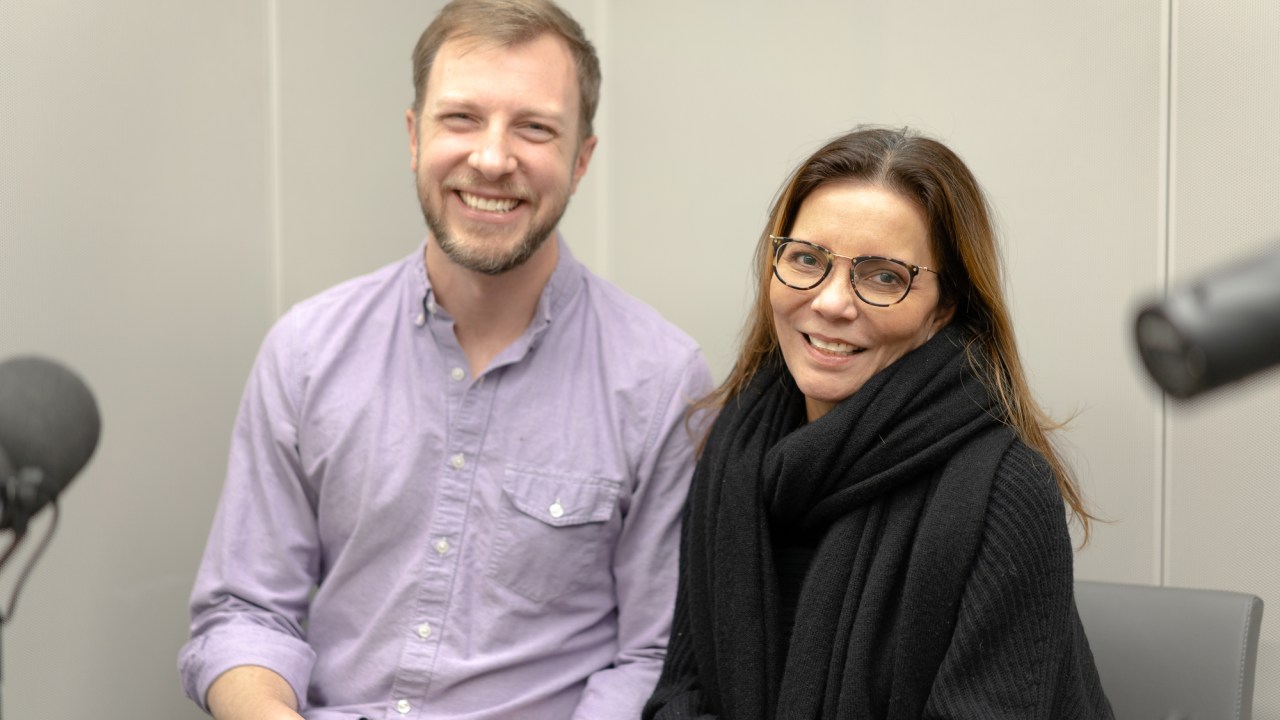 The podcast host is seen in the recording studio with a guest.