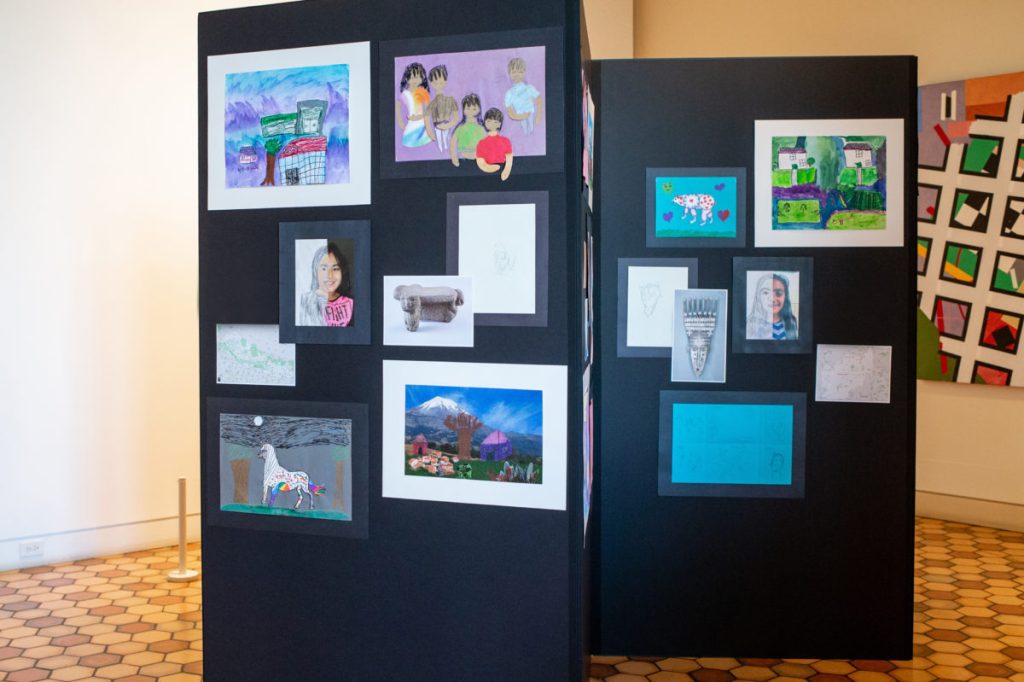 Temporary gallery walls with matted artworks on them, self-portraits in the middle and miscellaneous illustrations surrounding them.