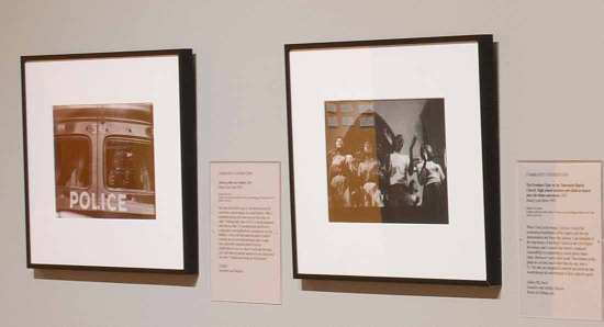 Two framed photographs on a gallery wall, one showing the back window of a police car.