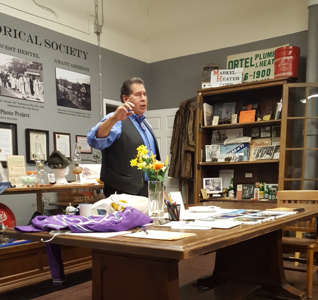 Jemison is seen in front of a table displaying artifacts as he speaks to the group.