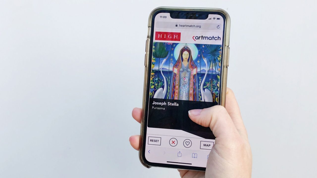A person holds a smartphone open on the app, which shows an image and credit line for a painting.