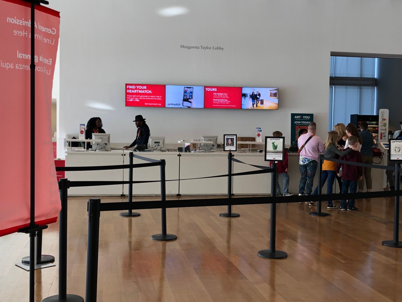 The ticket line in the lobby of the museum shows signs advertising Heartmatch on top of stanchions and on a TV screen behind the desk.