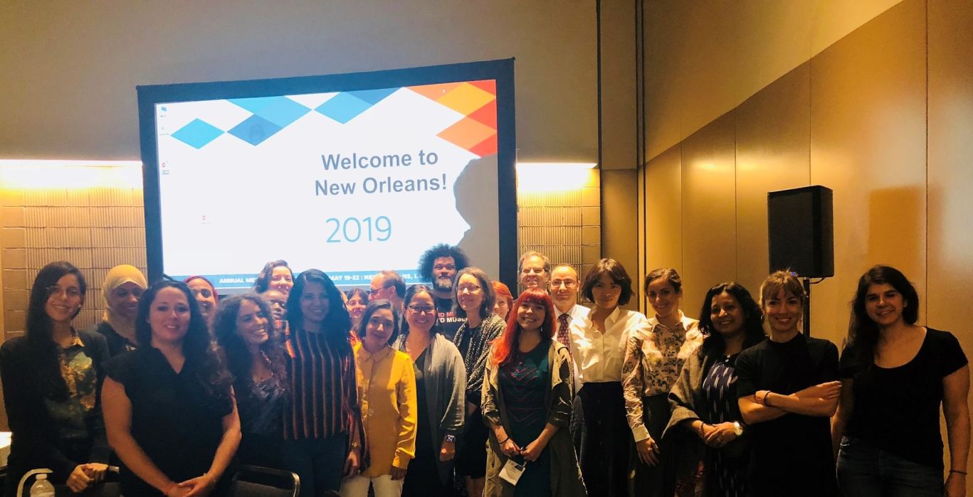 A group shot in front of a screen that reads "Welcome to New Orleans!"