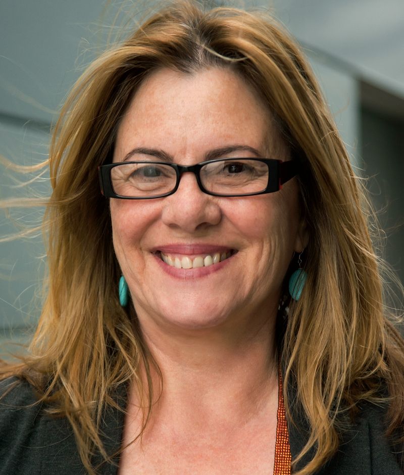Photo of Ann Burroughs. She is smiling with shoulder length light brown hair and glasses.