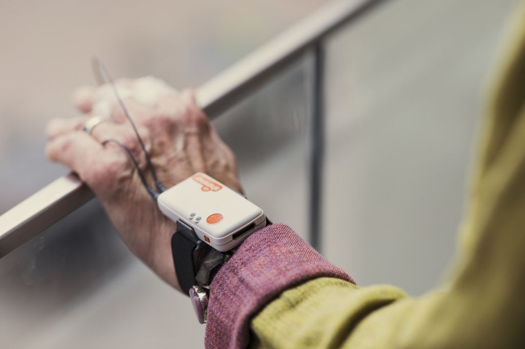 A study participants is wearing a device on a strap around their wrist.