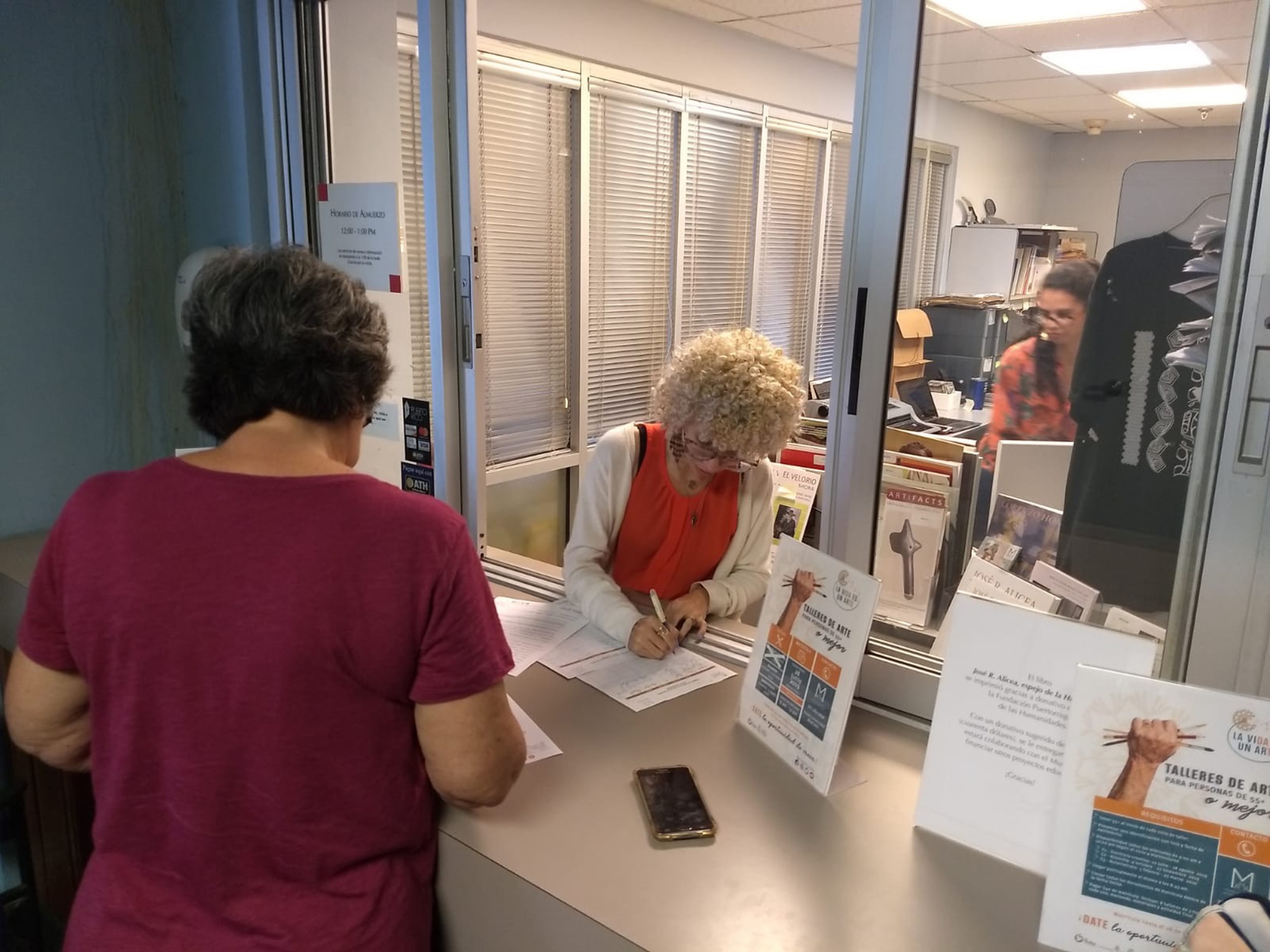 A visitor comes to a front desk to enroll in the program.
