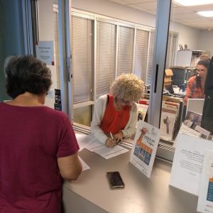 A visitor comes to a front desk to enroll in the program.