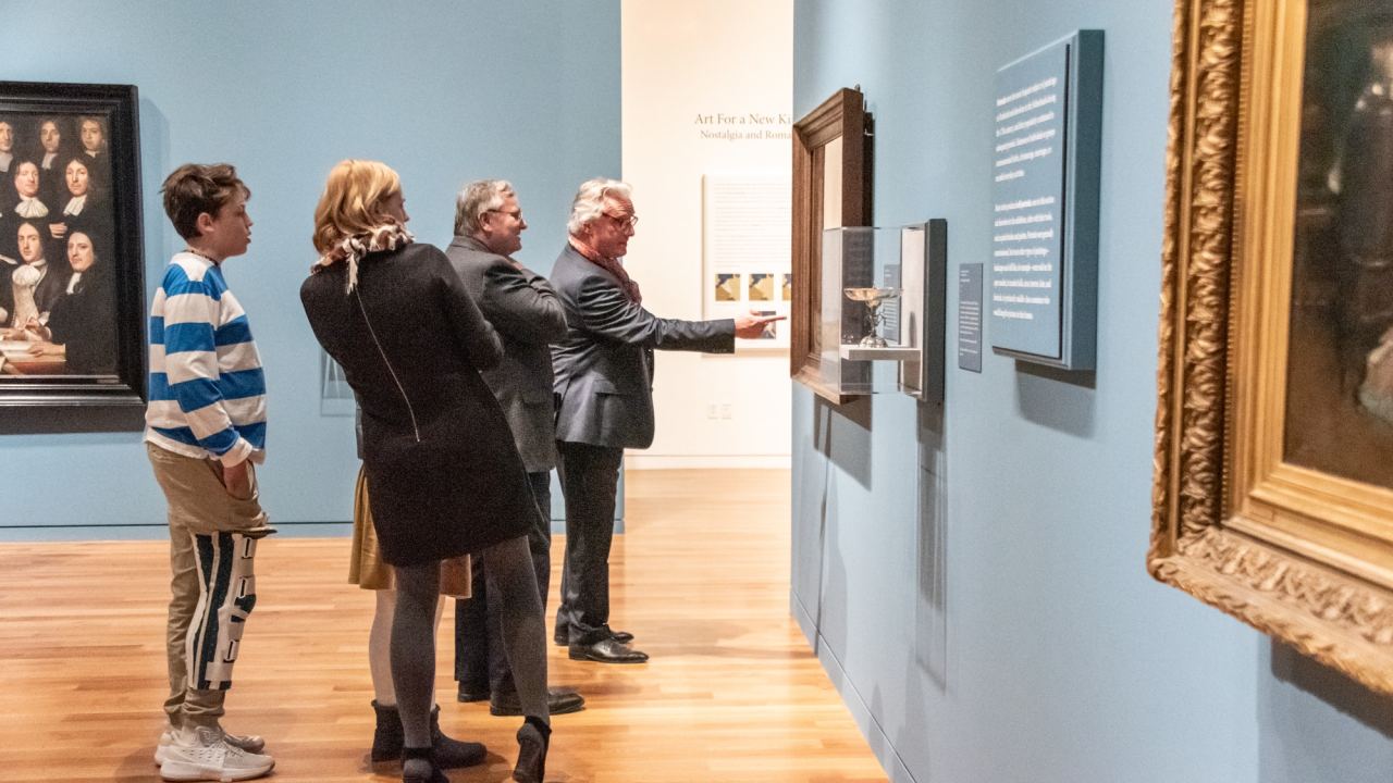 A group of visitors look at a canvas on display in an exhibition.