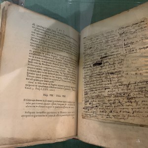 An open copy of an antique book on display, with handwritten annotations visible.
