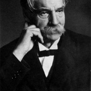 Black-and-white portrait photograph of a man in a tuxedo, with his signature underneath.