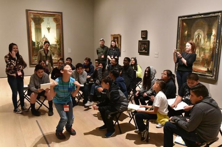 Surrounded by smiling and laughing classmates and instructors, a student performs a playful dance.