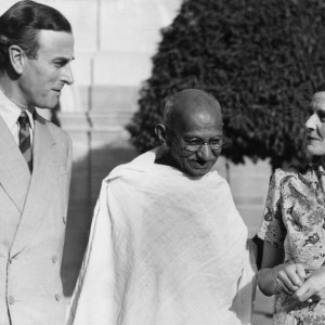 A black-and-white photograph of Gandhi posed with English royalty.