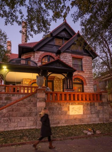 The outside of a historic Victorian home seen at dusk.