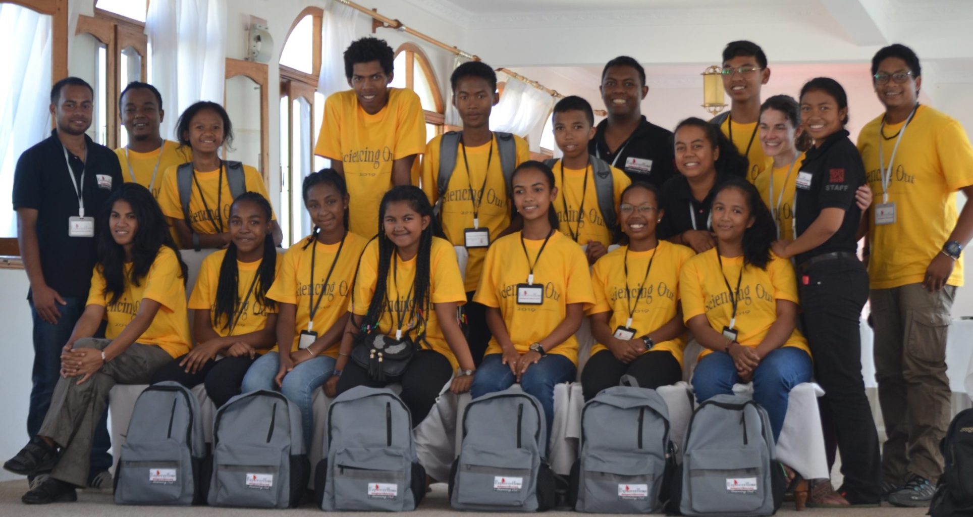 A group shot of students wearing lanyards and holding backpacks.