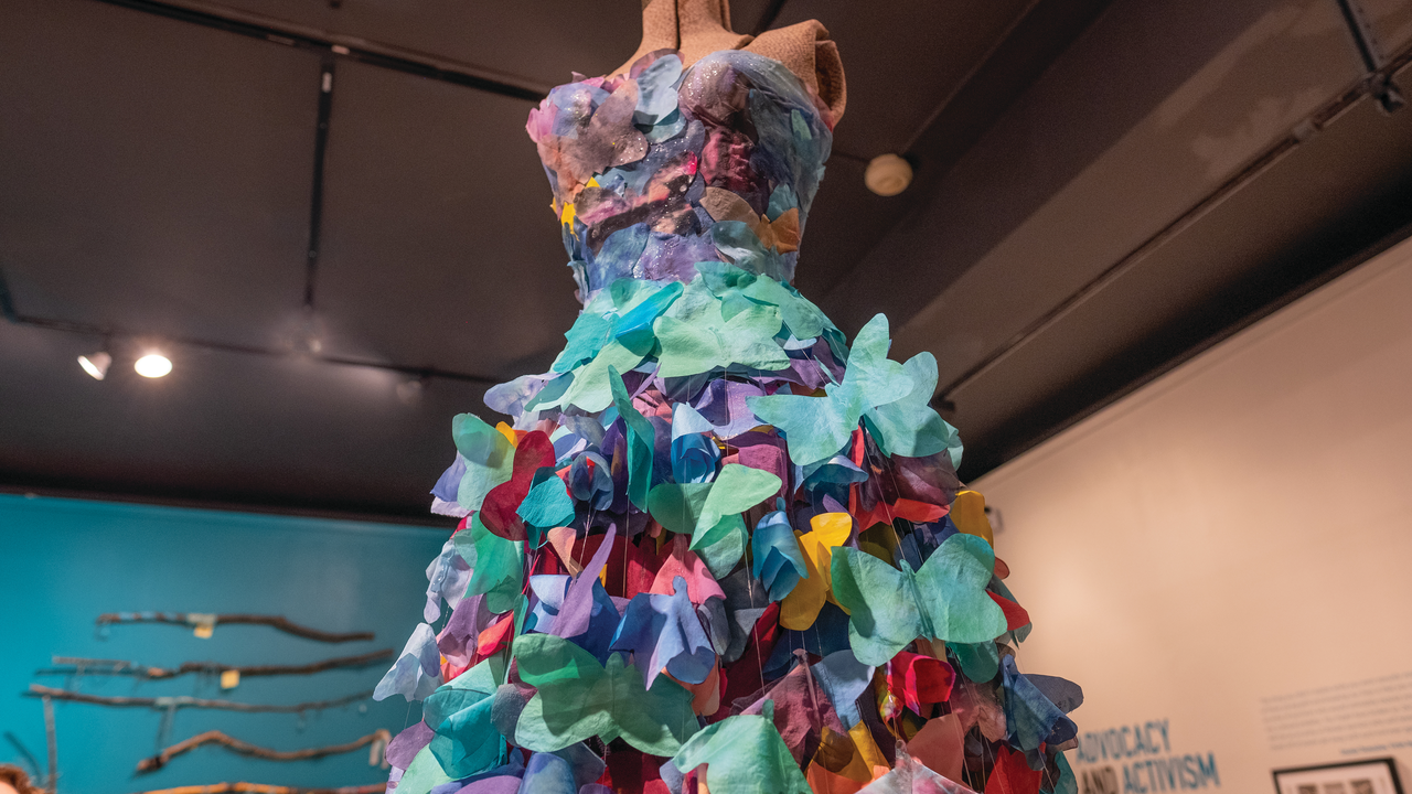 A mannequin figure in a dress made from many different colored paper butterflies.