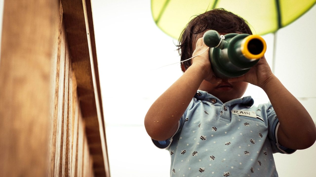 A young child looks through binoculars.