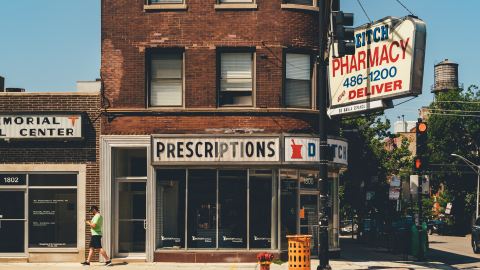 An old corner pharmacy that says "prescriptions" on the sign.