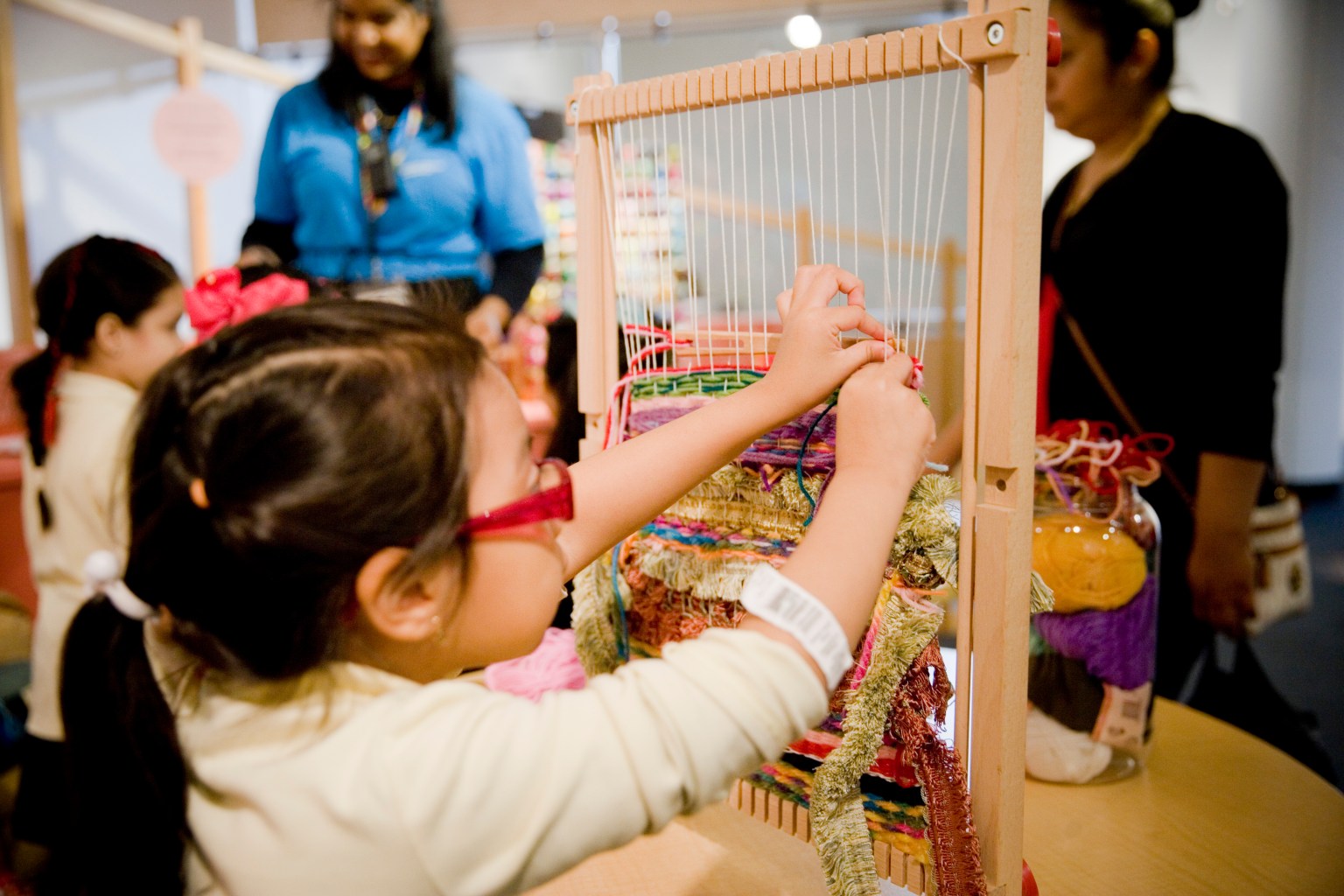 A young child experiments with weaving in a museum space.