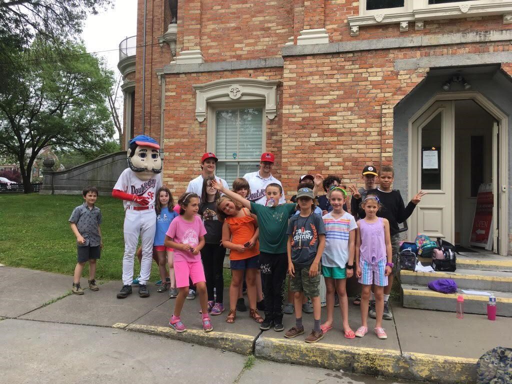 Campers pose for a group portrait in front of a museum with someone in an Abner Doubleday costume.