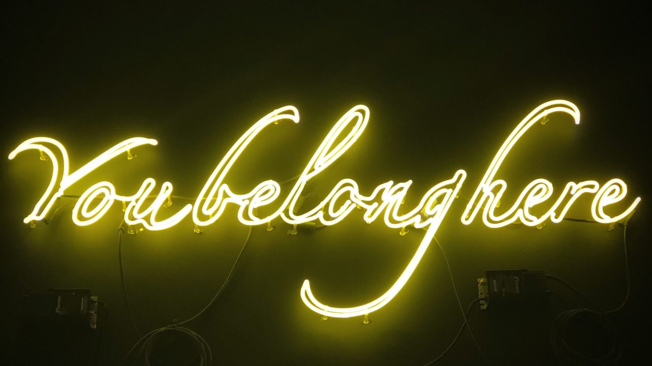 A neon sign that reads "You Belong Here" in cursive.