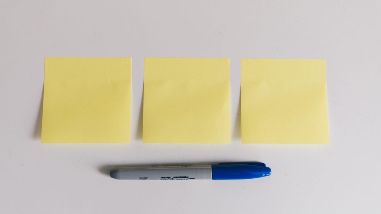 Three sticky notes and a blue Sharpie laid out on a table
