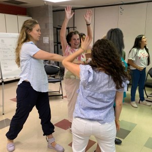 The teaching artist instructs participants who are moving their arms.