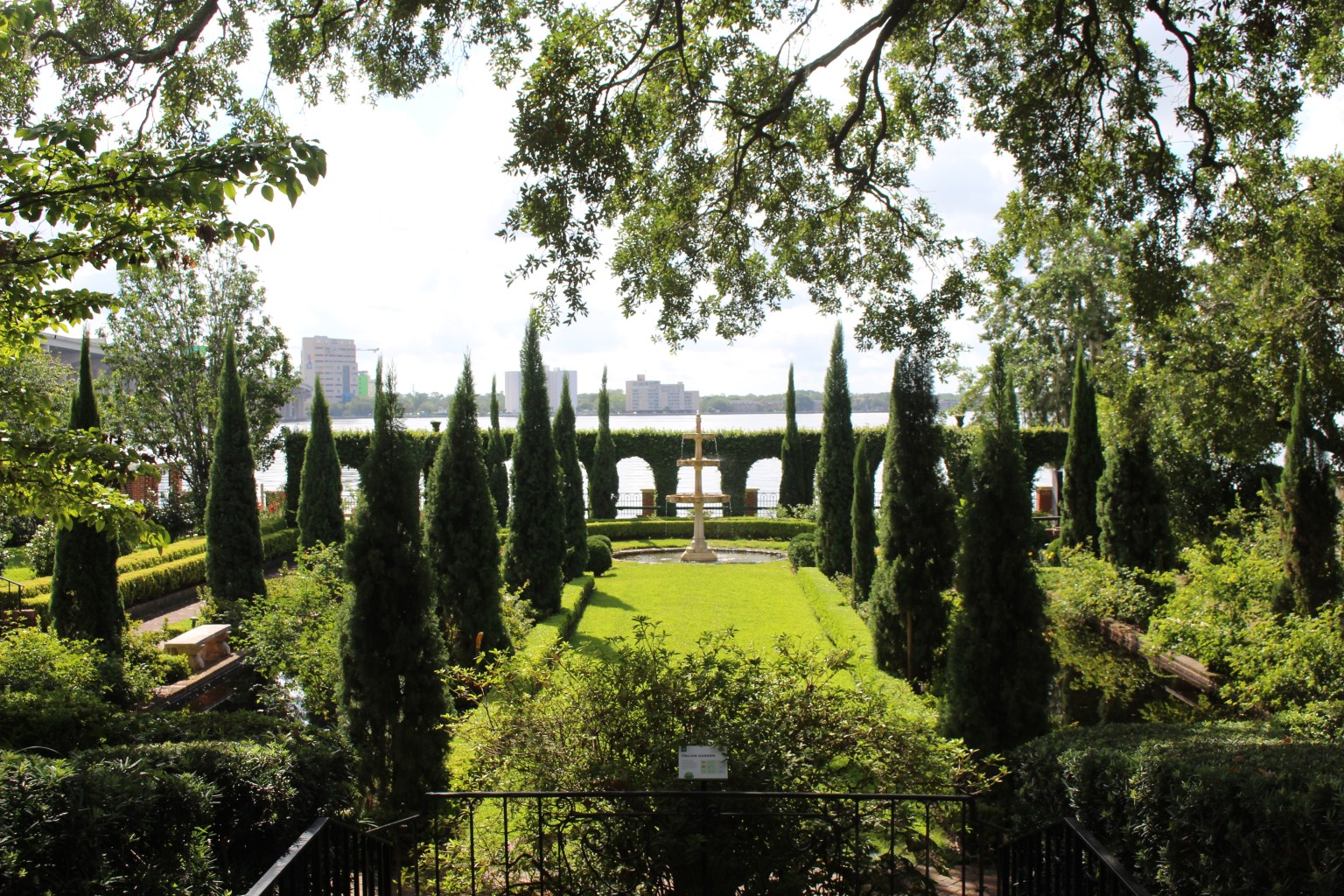 A geometrically arranged garden facing a city waterfront.