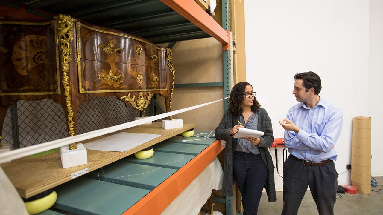 Two museum professionals stand in a collections store space.
