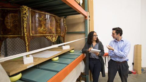 Two museum professionals stand in a collections store space.