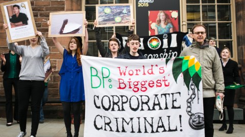 A group of individuals stand with protest signs the largest of which says, "BP: World's Biggest Corporate Criminal!"