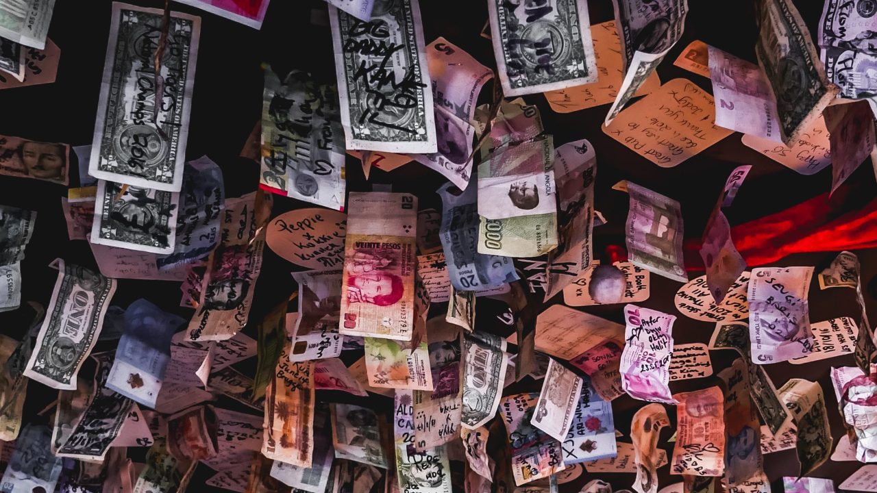 Banknotes of different currencies hanging from a ceiling