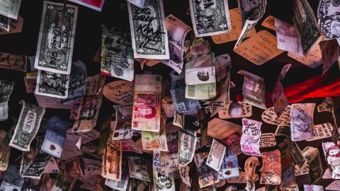 Banknotes of different currencies hanging from a ceiling
