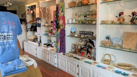 Interior of a museum store with objects like woven baskets and museum t-shirts on sale.
