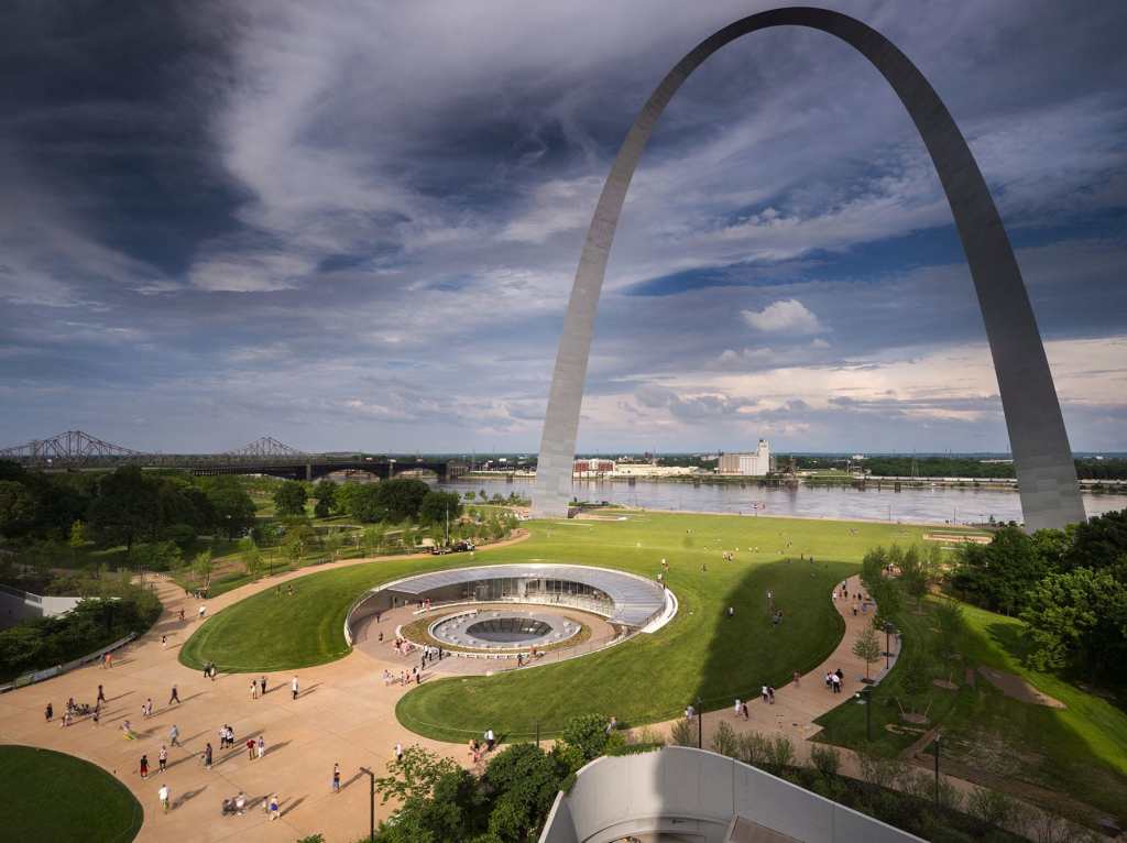 At the foot of the monumental Gateway Arch, a round entryway leads to a museum, flanked by two surrounding walkways.