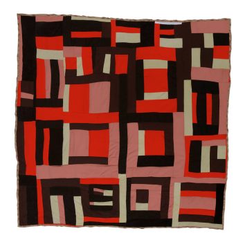 A quilt made up of curving, irregular strips of red, black, and grey fabric.