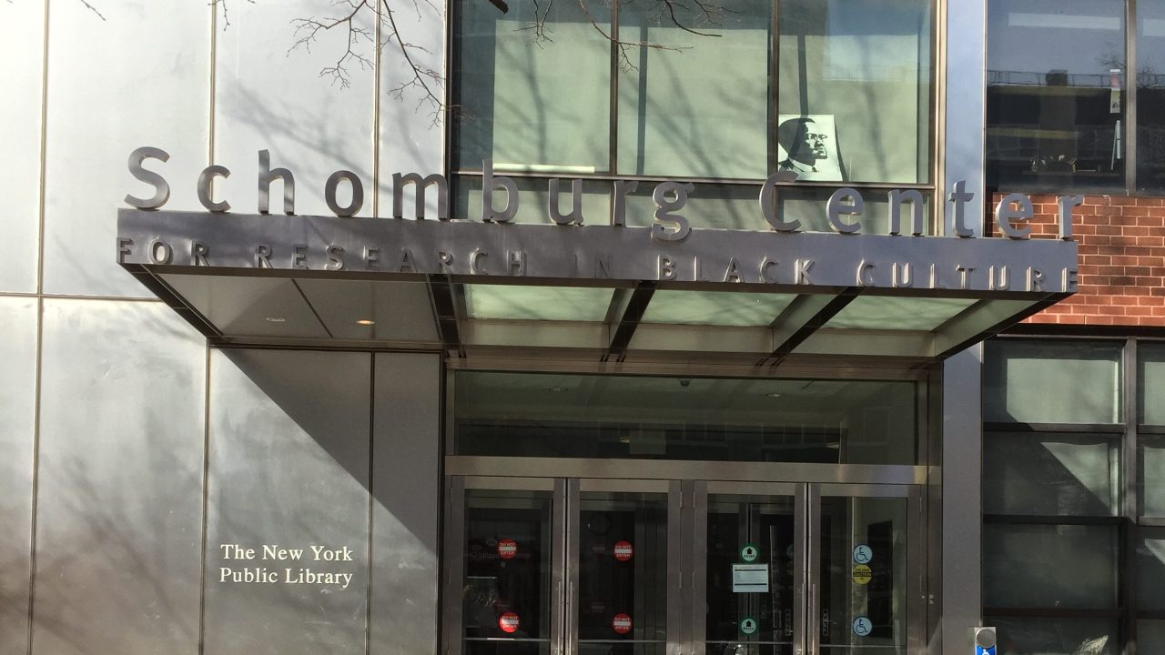 The facade of a building with a sign that reads "Schomburg Center for Research in Black Culture," with "The New York Public Library" underneath.