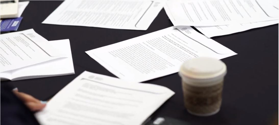 Various papers strewn across a black table clothed table.