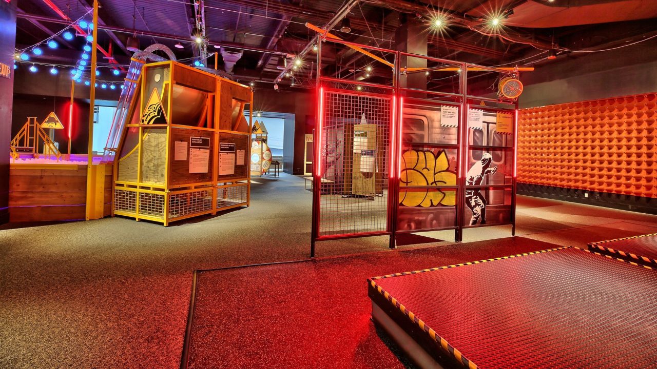 A museum space with padded walls and flooring and an image of subway graffiti on display