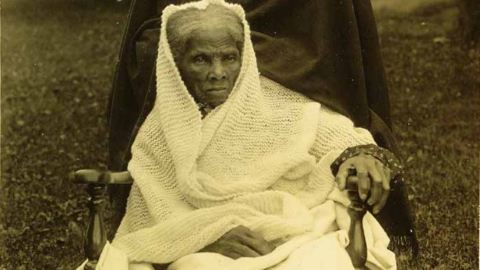 Harriet Tubman sits in a wheelchair wrapped in a knitted blanket.