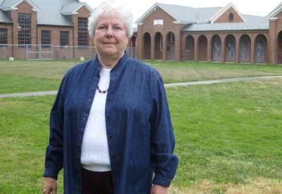 Clifton posing on a lawn in front of brick buildings