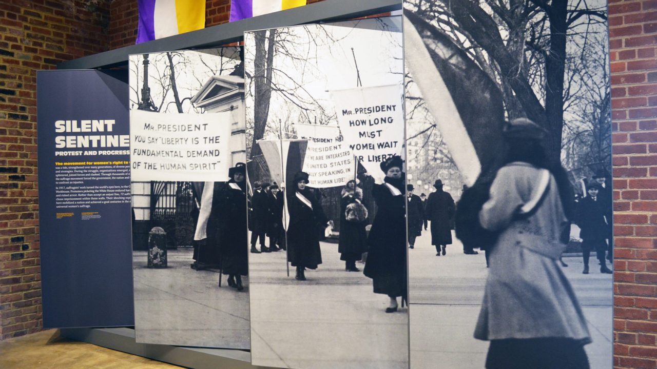 A panel display titled "Silent Sentinels" shows suffragists protesting in front of the White House with signs.