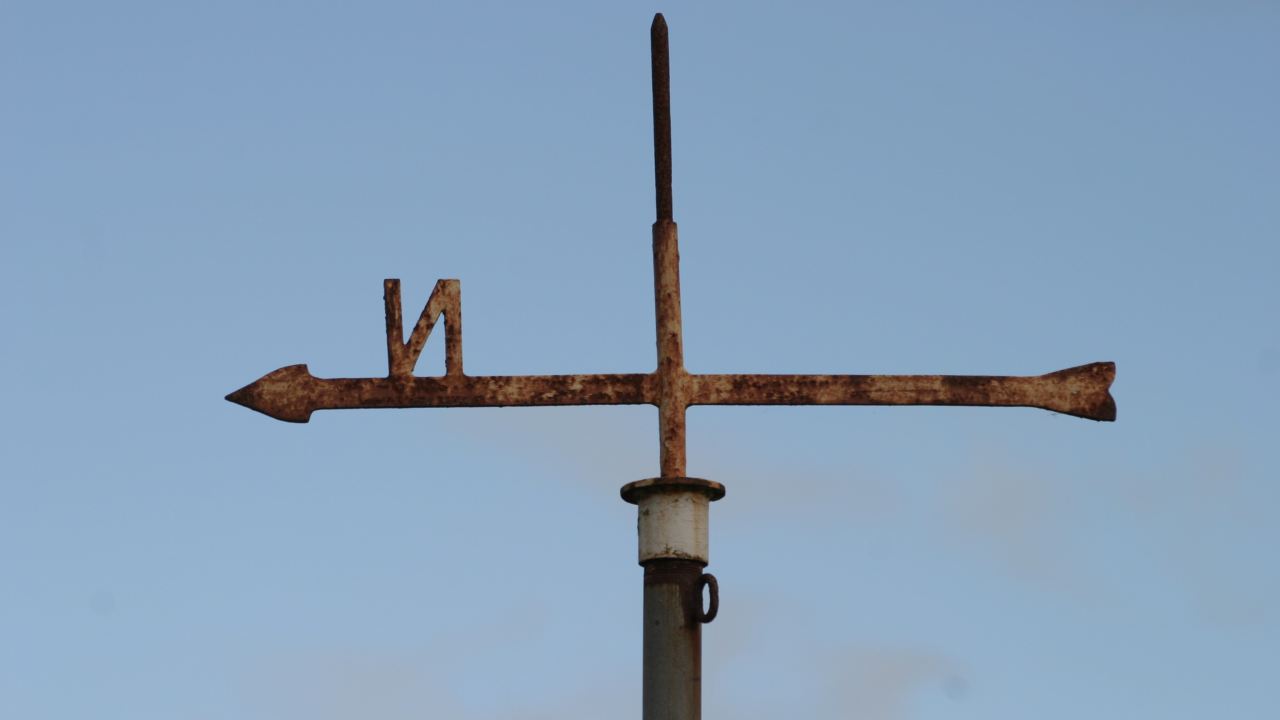 A weathervane with the arrow and letter N pointing backward