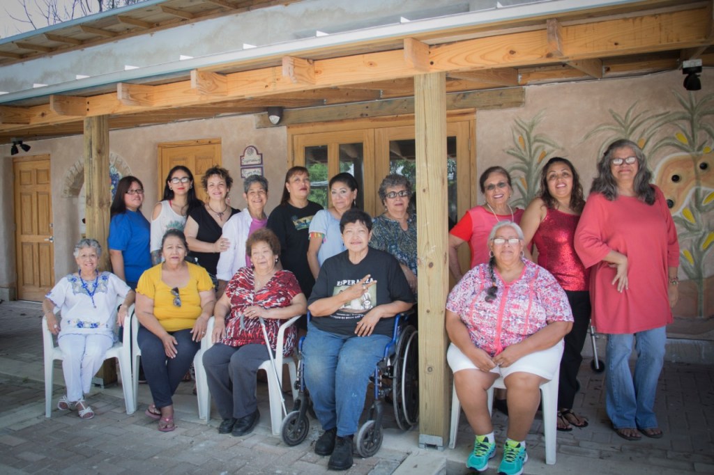 A group of people posing under the portal of an adobe building