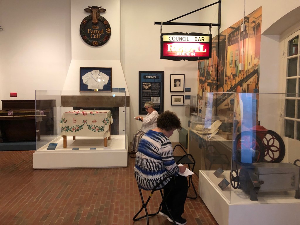 Participants sitting in front of objects on display in the museum with sketchpads