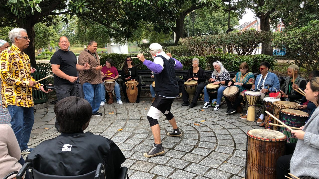 People sitting around in a drum circle while others dance in the middle